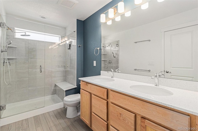 9757 Ash Ln, Thornton, CO 80229 - bathroom with a stall shower, double vanity, wood finished floors, and toilet