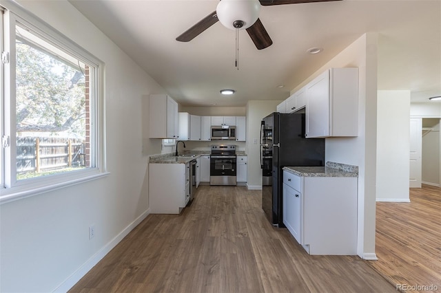 6013 W 62nd Ave, Arvada, CO 80033 - kitchen featuring stainless steel appliances, a sink, light wood finished floors, and white cabinetry