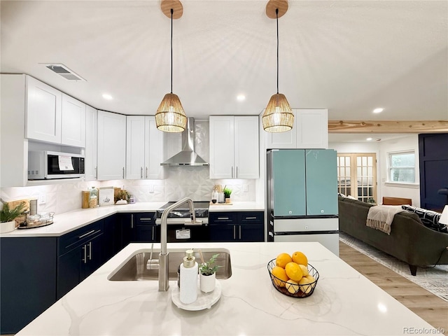 1360 W Custer Pl, Denver, CO 80223 - kitchen with white microwave, fridge, wall chimney range hood, pendant lighting, and recessed lighting