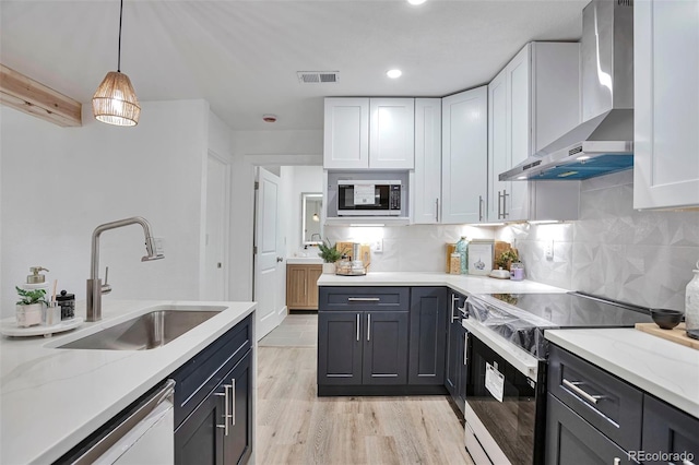 1360 W Custer Pl, Denver, CO 80223 - kitchen featuring black electric range oven, wall chimney range hood, dishwashing machine, light wood-style floors, and white cabinetry