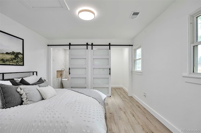 1360 W Custer Pl, Denver, CO 80223 - bedroom featuring a barn door and light wood-type flooring
