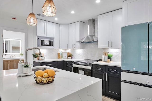 1360 W Custer Pl, Denver, CO 80223 - kitchen with fridge, wall chimney exhaust hood, range with electric stovetop, white cabinets, and dark cabinetry