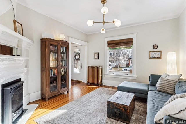 living room with ornamental molding, radiator, a chandelier, and light wood-type flooring