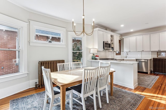 dining space with radiator, sink, and light hardwood / wood-style flooring