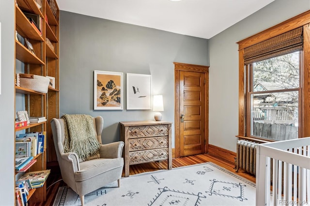 living area with radiator heating unit and hardwood / wood-style floors