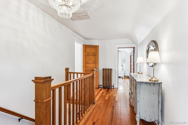 hallway featuring lofted ceiling, radiator, wood-type flooring, and a chandelier