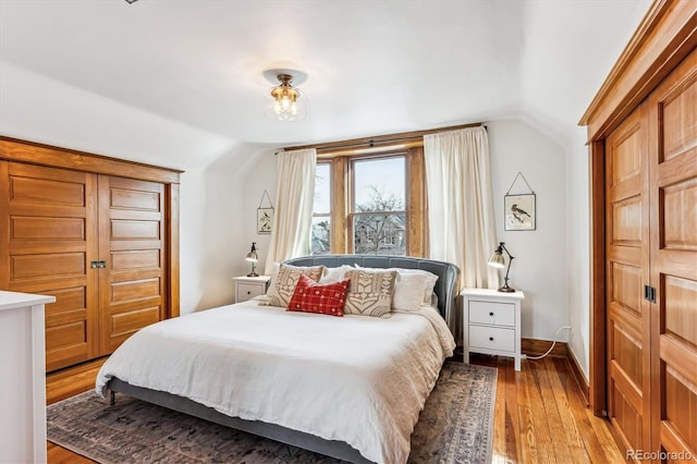 bedroom with vaulted ceiling and light hardwood / wood-style flooring