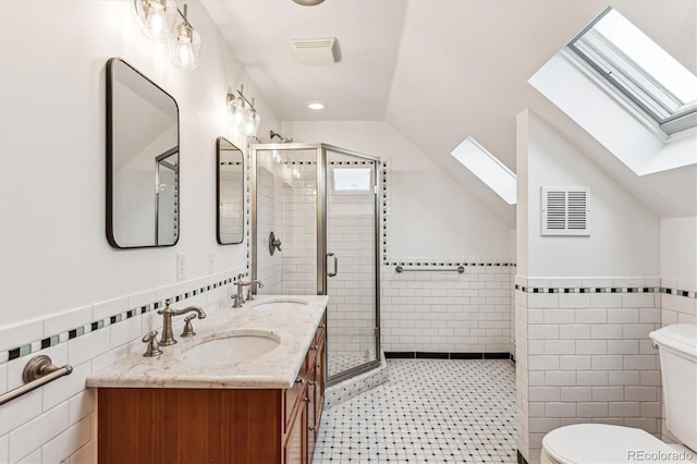 bathroom with vaulted ceiling with skylight, a shower with shower door, tile walls, and toilet