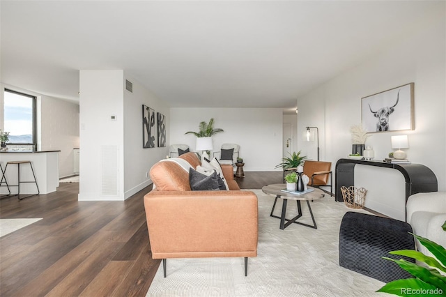 living area with visible vents, baseboards, and wood finished floors