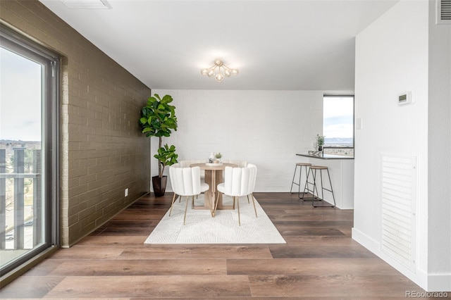 dining area with plenty of natural light, wood finished floors, and brick wall