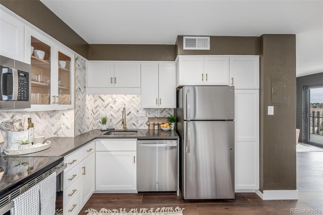 kitchen featuring dark wood-style floors, visible vents, a sink, stainless steel appliances, and glass insert cabinets