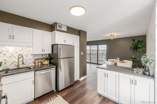 kitchen featuring dark wood-type flooring, decorative backsplash, white cabinets, stainless steel appliances, and a sink