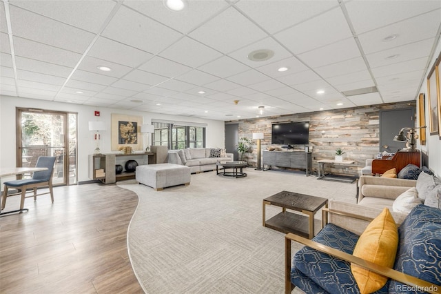 living area with wooden walls, recessed lighting, wood finished floors, and a paneled ceiling