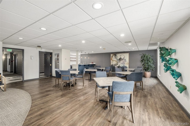 dining area with recessed lighting, wood finished floors, baseboards, and a paneled ceiling