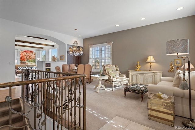 living room featuring beam ceiling, light carpet, and a notable chandelier