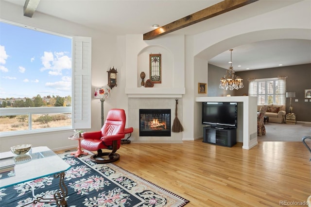 sitting room with a notable chandelier, plenty of natural light, beam ceiling, and light hardwood / wood-style flooring