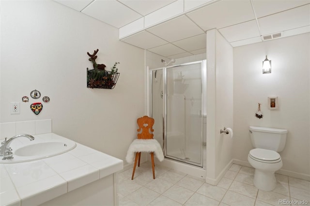 bathroom with tile patterned flooring, a paneled ceiling, toilet, and walk in shower