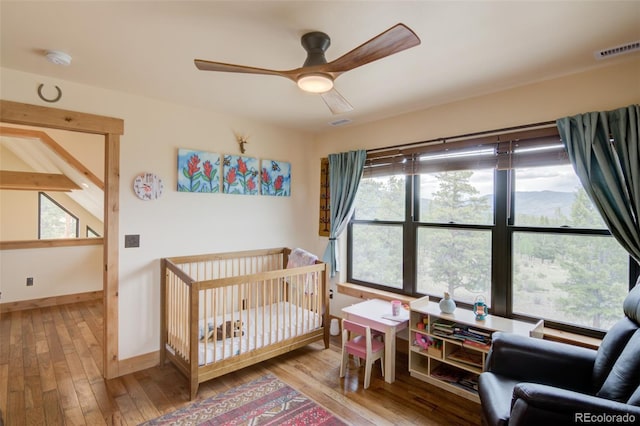 30490 Harvard Cir, Buena Vista, CO 81211 - bedroom with hardwood / wood-style flooring, baseboards, a crib, and a ceiling fan