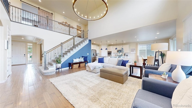 5932 Eldora St, Golden, CO 80403 - living room featuring arched walkways, stairs, a high ceiling, baseboards, and light wood-type flooring