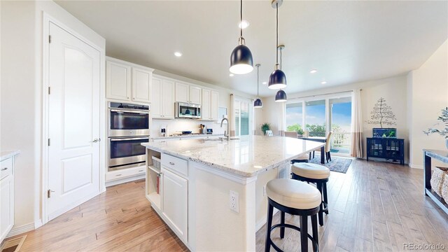 5932 Eldora St, Golden, CO 80403 - kitchen with appliances with stainless steel finishes, a sink, light wood finished floors, white cabinetry, and recessed lighting