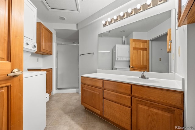 bathroom featuring a shower stall, toilet, vanity, and stacked washer and dryer