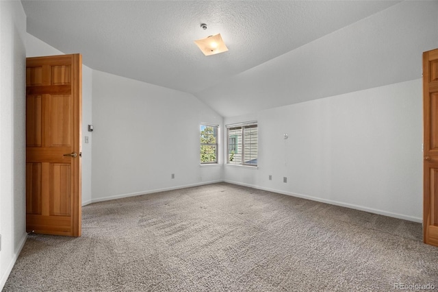 spare room featuring baseboards, light carpet, a textured ceiling, and lofted ceiling