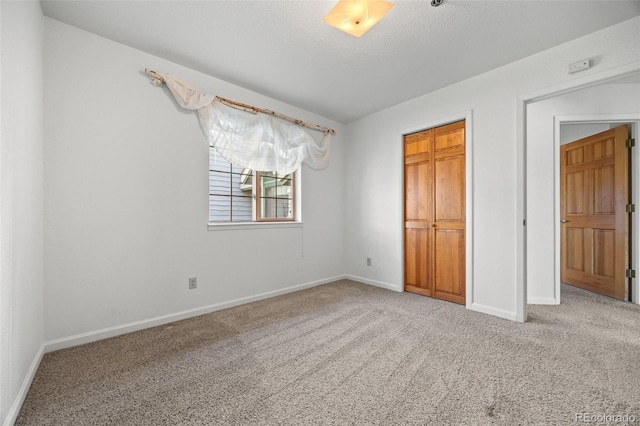 unfurnished bedroom with carpet, baseboards, a closet, and a textured ceiling