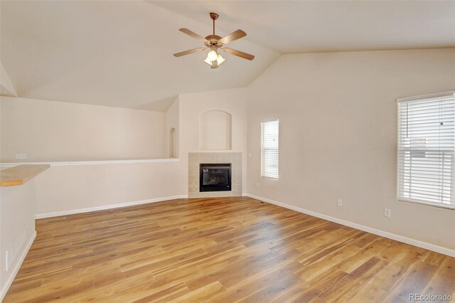 6836 Loudon St, Wellington, CO 80549 - unfurnished living room featuring healthy amount of natural light, vaulted ceiling, ceiling fan, light wood finished floors, and a tiled fireplace