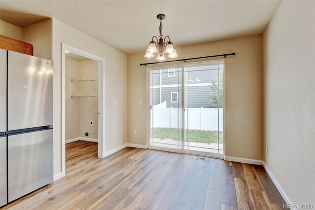 6836 Loudon St, Wellington, CO 80549 - unfurnished dining area with a chandelier, light wood-style floors, and healthy amount of natural light