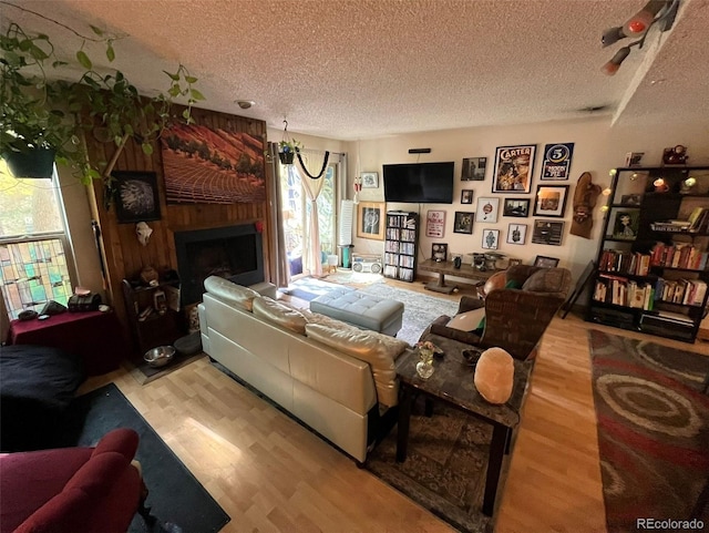 living room with a textured ceiling, light hardwood / wood-style flooring, and a brick fireplace