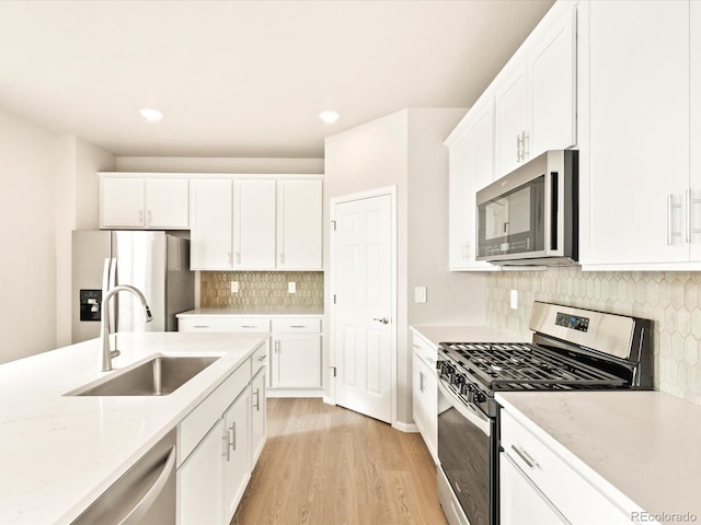 kitchen featuring light stone countertops, appliances with stainless steel finishes, white cabinets, and sink