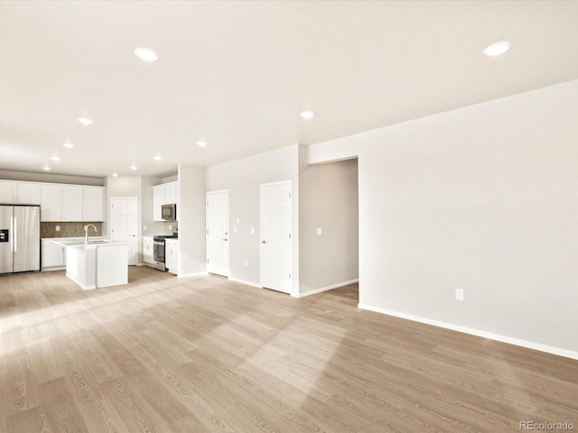 unfurnished living room featuring sink and light hardwood / wood-style flooring