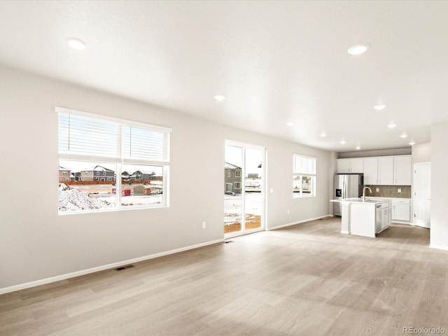 unfurnished living room featuring light wood-type flooring and sink