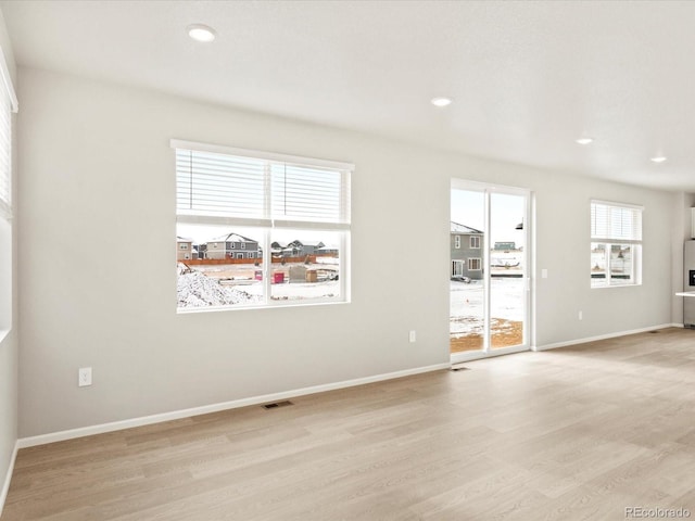 spare room featuring light hardwood / wood-style floors and a healthy amount of sunlight