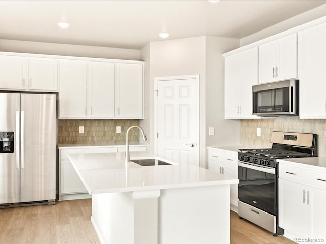 kitchen with light hardwood / wood-style floors, sink, white cabinetry, appliances with stainless steel finishes, and an island with sink