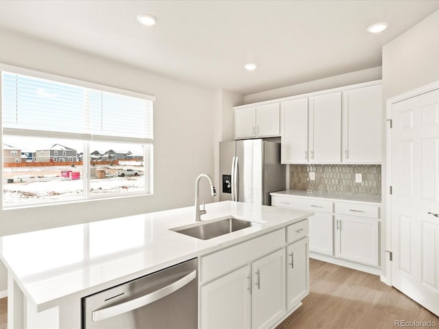 kitchen with white cabinetry, stainless steel appliances, tasteful backsplash, sink, and a kitchen island with sink