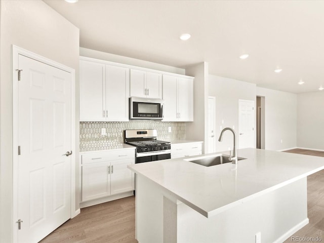 kitchen with backsplash, a center island with sink, sink, appliances with stainless steel finishes, and white cabinets