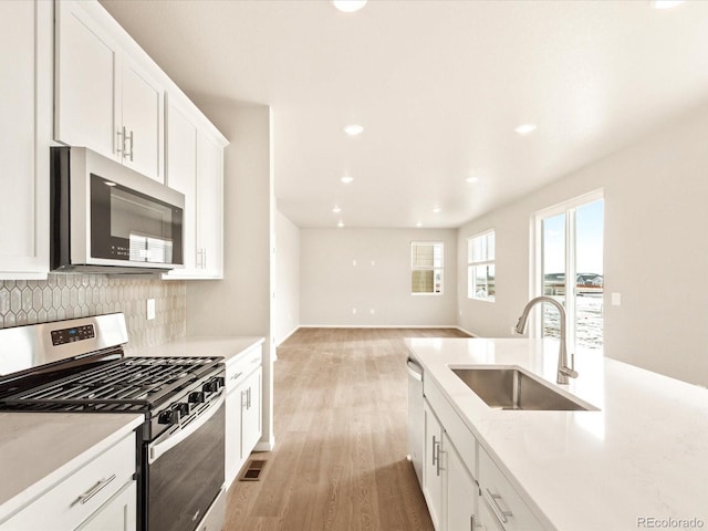 kitchen featuring light hardwood / wood-style floors, decorative backsplash, sink, appliances with stainless steel finishes, and white cabinets