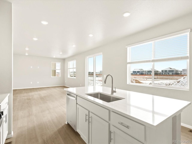 kitchen featuring light hardwood / wood-style floors, an island with sink, dishwasher, white cabinets, and sink