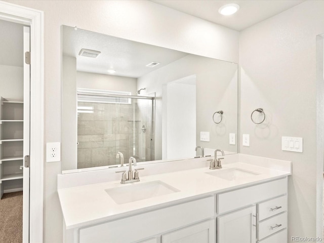 bathroom featuring a shower with shower door and vanity