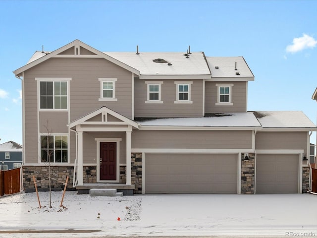 view of front of property with stone siding, fence, and an attached garage