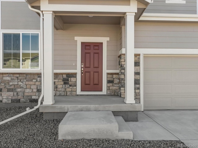 doorway to property featuring a garage and stone siding