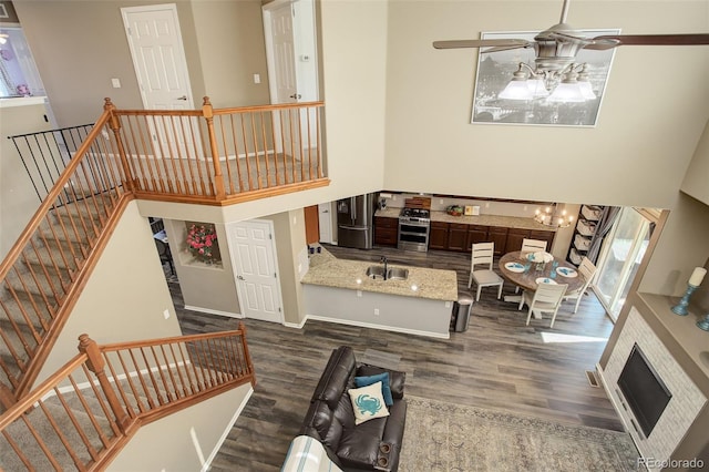 15122 Fillmore Way, Thornton, CO 80602 - living area featuring dark wood-type flooring, a towering ceiling, ceiling fan, a chandelier, and stairs