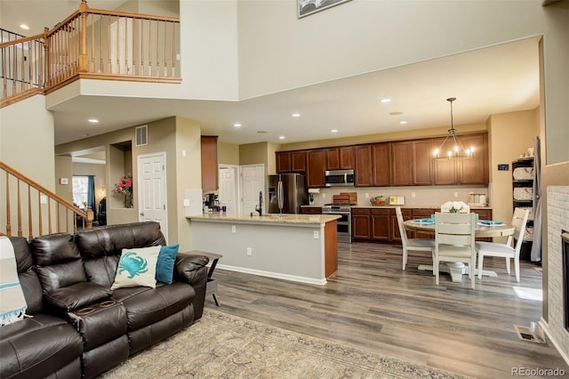15122 Fillmore Way, Thornton, CO 80602 - living area featuring wood finished floors, stairs, recessed lighting, a high ceiling, and a chandelier