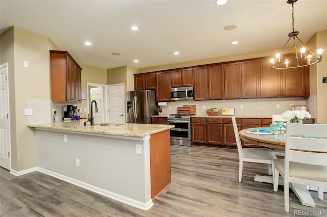 15122 Fillmore Way, Thornton, CO 80602 - kitchen with stainless steel appliances, a chandelier, a peninsula, light wood-style floors, and light stone countertops
