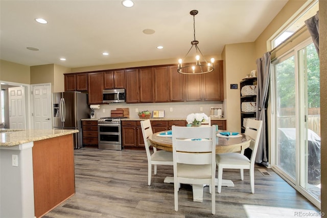 15122 Fillmore Way, Thornton, CO 80602 - kitchen featuring appliances with stainless steel finishes, a chandelier, light wood-type flooring, hanging light fixtures, and recessed lighting