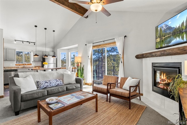 living area featuring light carpet, a fireplace with flush hearth, a wealth of natural light, and beamed ceiling