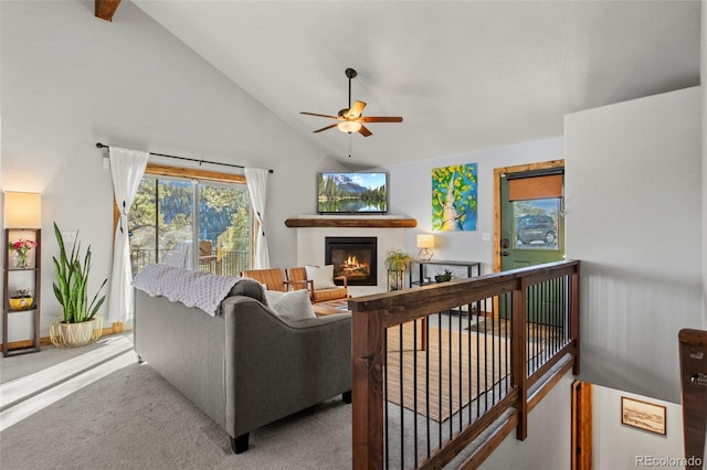 living area featuring ceiling fan, carpet floors, high vaulted ceiling, and a glass covered fireplace