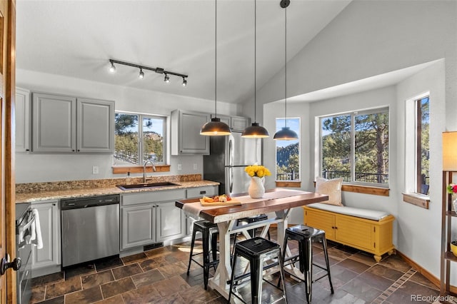 kitchen featuring appliances with stainless steel finishes, stone finish floor, a sink, and gray cabinetry