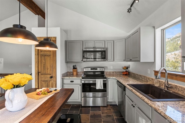 kitchen with lofted ceiling, stainless steel appliances, a sink, hanging light fixtures, and gray cabinets